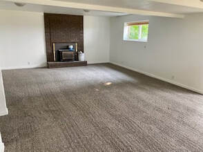 A picture of several perfectly straight vacuum tracks in a large grey carpet in a vacant living room.