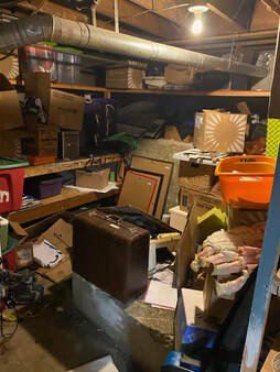 Picture of cluttered, chaotic, unorganized belongings in a basement storage area. piles of