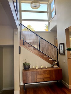 Picture of a front entrance or foyer in a home that is beautifully clean and uncluttered. There is a staircase leading to the second floor and a row of crystal-clear, sunlit windows above the stair case.